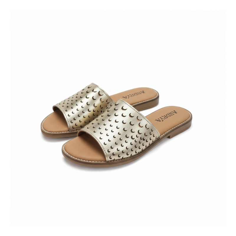 Feito para quem não abdica do estilo mesmo nos dias mais descontraídos, este chinelo raso em couro metalizado dourado é uma peça que combina conforto e sofisticação com naturalidade.
A tira larga em pele com acabamento metálico dourado apresenta um padrão de recortes em forma de lua crescente, um detalhe que confere leveza visual e um toque editorial ao design.