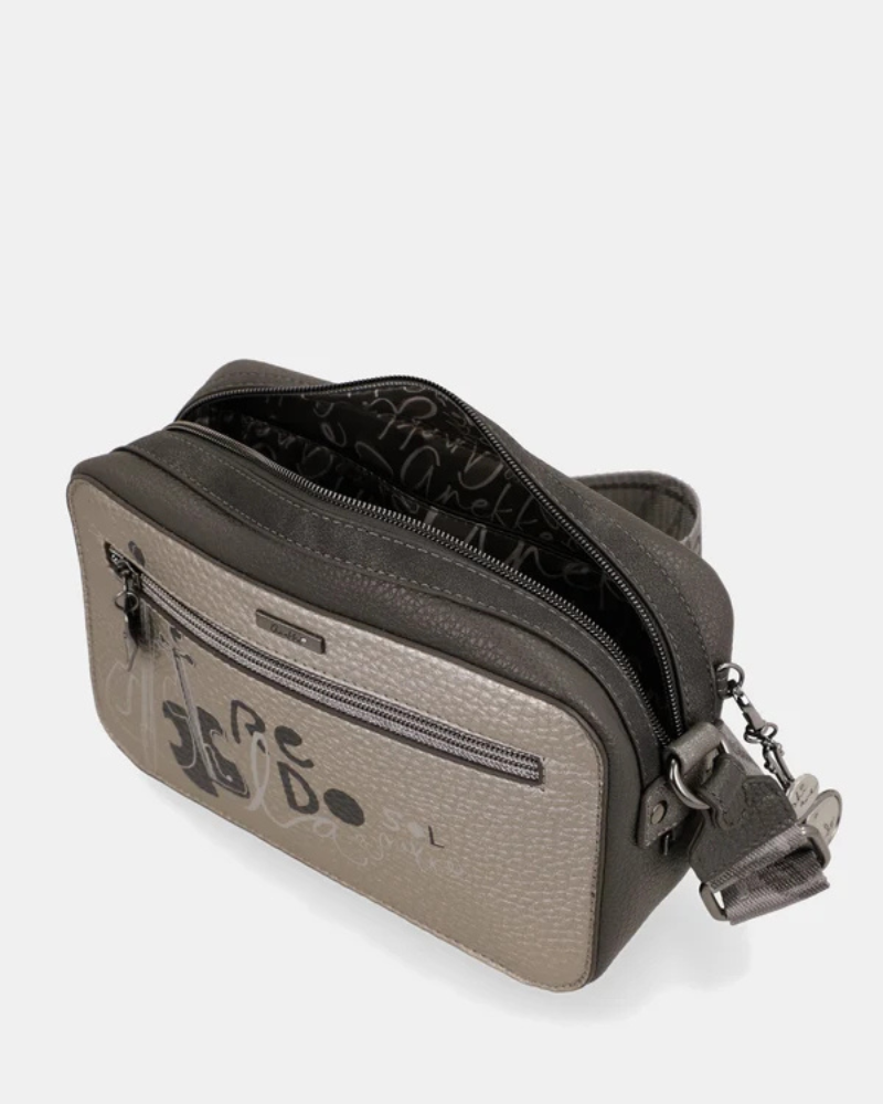 Esta carteira é a companheira perfeita para quem procura estilo e praticidade num formato compacto.
Com uma silhueta retangular e estrutura rígida, esta carteira destaca-se pelo seu acabamento metálico prateado com reflexos pérola, que lhe confere um aspeto sofisticado e contemporâneo. A parte frontal apresenta a ilustração exclusiva da personagem Anekke numa cenografia de inspiração clássica e musical, com detalhes arquitetónicos e elementos de cena que tornam cada peça verdadeiramente única.