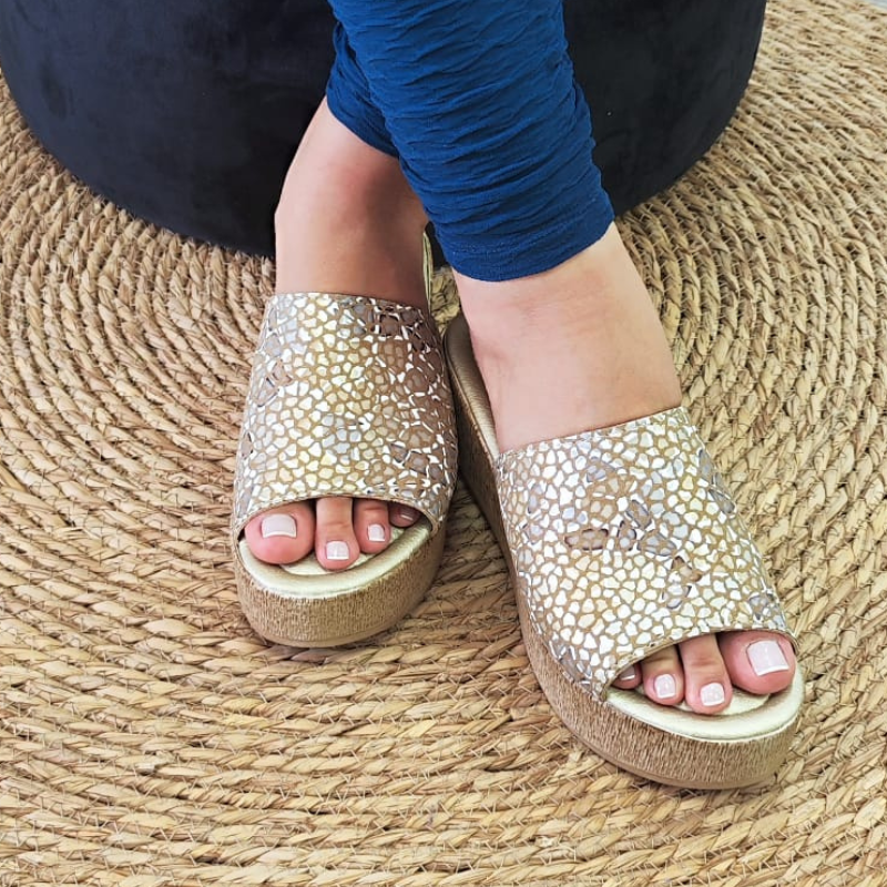 Confortável e elegante, o chinelo de cunha proporciona altura e elegância, enquanto a pele confere durabilidade e estilo ao chinelo. A tira larga na parte superior do pé, proporciona sustentação e segurança ao caminhar. Este chinelo de cunha é uma opção sofisticada e confortável para quem procura um calçado versátil. Pode ser usado em diversas ocasiões, tanto durante o dia quanto à noite. Combina bem com looks casuais, como vestidos soltos, calções, saias e calças de ganga. Made in Portugal