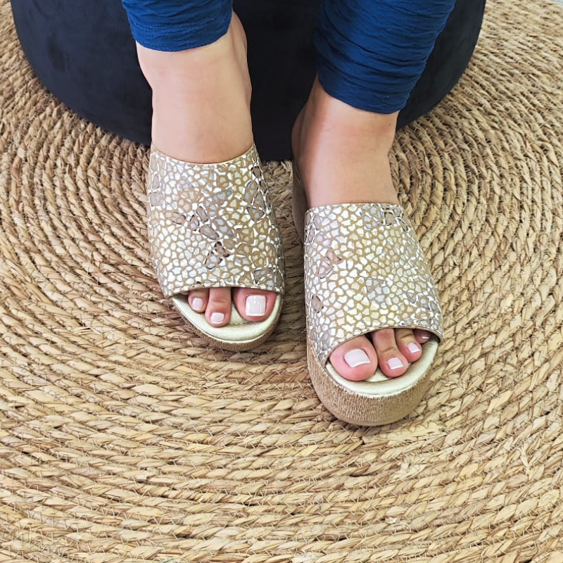 Confortável e elegante, o chinelo de cunha proporciona altura e elegância, enquanto a pele confere durabilidade e estilo ao chinelo. A tira larga na parte superior do pé, proporciona sustentação e segurança ao caminhar. Este chinelo de cunha é uma opção sofisticada e confortável para quem procura um calçado versátil. Pode ser usado em diversas ocasiões, tanto durante o dia quanto à noite. Combina bem com looks casuais, como vestidos soltos, calções, saias e calças de ganga. Made in Portugal