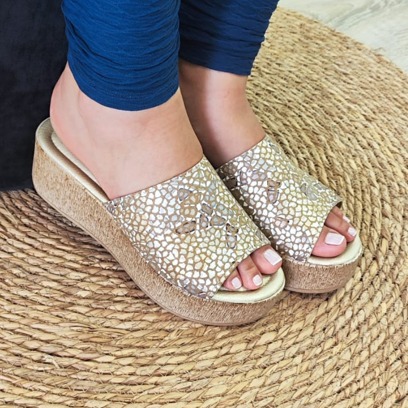 Confortável e elegante, o chinelo de cunha proporciona altura e elegância, enquanto a pele confere durabilidade e estilo ao chinelo. A tira larga na parte superior do pé, proporciona sustentação e segurança ao caminhar. Este chinelo de cunha é uma opção sofisticada e confortável para quem procura um calçado versátil. Pode ser usado em diversas ocasiões, tanto durante o dia quanto à noite. Combina bem com looks casuais, como vestidos soltos, calções, saias e calças de ganga. Made in Portugal