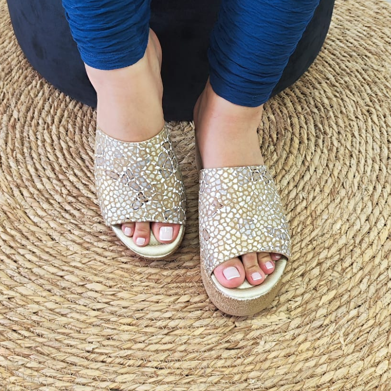 Confortável e elegante, o chinelo de cunha proporciona altura e elegância, enquanto a pele confere durabilidade e estilo ao chinelo. A tira larga na parte superior do pé, proporciona sustentação e segurança ao caminhar. Este chinelo de cunha é uma opção sofisticada e confortável para quem procura um calçado versátil. Pode ser usado em diversas ocasiões, tanto durante o dia quanto à noite. Combina bem com looks casuais, como vestidos soltos, calções, saias e calças de ganga. Made in Portugal