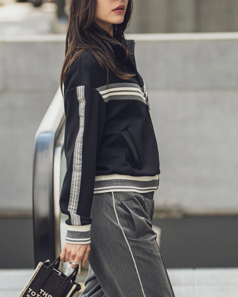 Este bomber combina o estilo desportivo com um toque urbano sofisticado, tornando-se uma peça versátil para compor looks confortáveis e cheios de personalidade.
Confeccionado em tecido macio, apresenta um corte descontraído e detalhes em tiras contrastantes nas mangas e no peito, que acrescentam dinamismo ao design. O fecho frontal em zíper oferece praticidade, enquanto os punhos, gola e barra canelados garantem um ajuste perfeito e maior conforto.