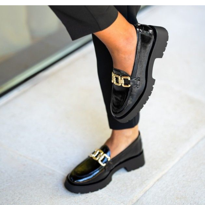 Este elegante sapato preto é a escolha perfeita para quem procura sofisticação e conforto.
Com acabamento em verniz, exibe um brilho discreto e moderno, complementado por uma corrente dourada na parte superior, conferindo um toque luxuoso ao design.