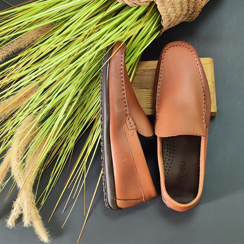 O sapato mocassim é um calçado clássico e versátil, perfeito para diversas ocasiões. Sem atacadores, desliza facilmente nos pés. Possui um estilo elegante e casual, com uma silhueta de bico arredondado e uma costura em torno da parte superior do calçado. Uma das características marcantes do mocassim é o seu conforto, este modelo é projetado para se ajustar aos pés e oferecer uma sensação de leveza ao caminhar. Made in Portugal