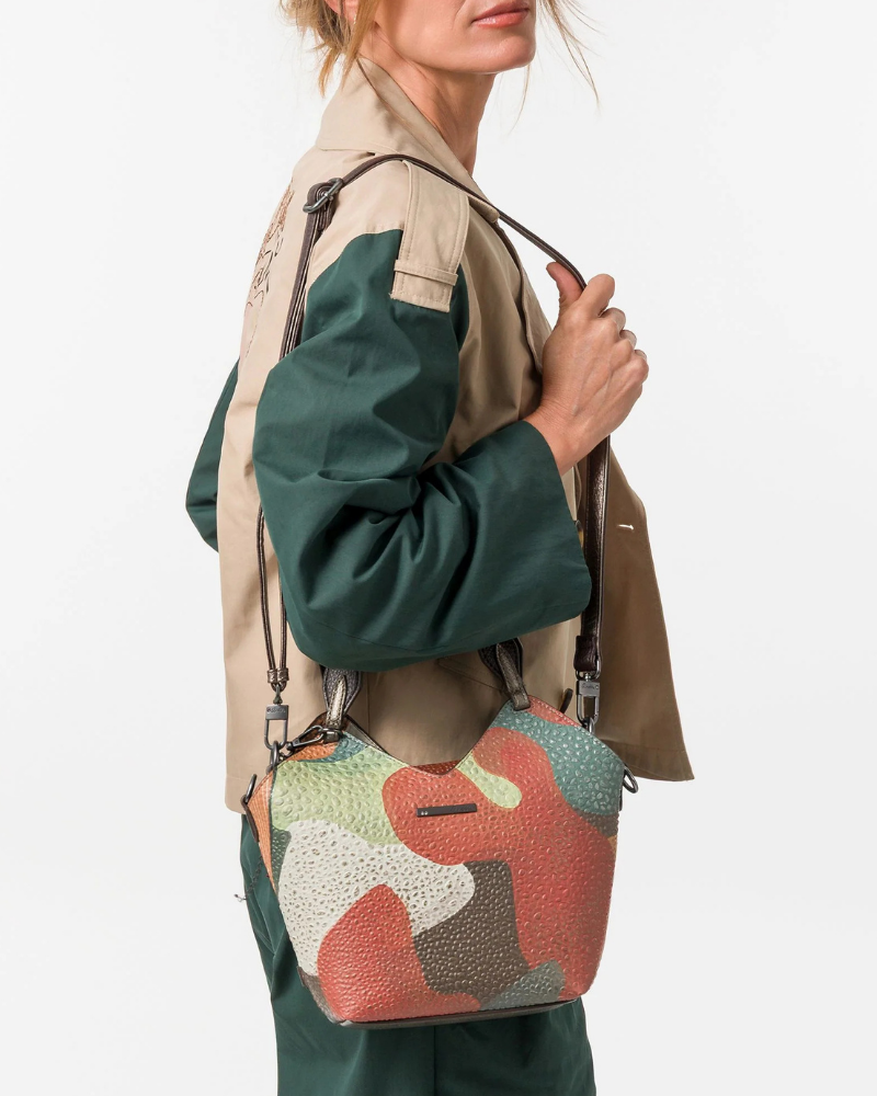 Esta carteira redefine o conceito de versatilidade com uma proposta única: duas carteiras numa só.

A bolsa principal impressiona pelo seu padrão artístico em tons de laranja, verde, bege e terracota, com uma textura trabalhada que evoca o espírito aventureiro e cosmopolita da coleção Odyssey. Os detalhes em metal gunmetal, a corrente com pendente em forma de nuvem e as alças em couro sintético castanho-escuro completam um visual rico e distinto.