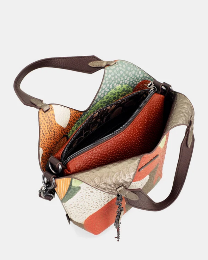 Esta carteira redefine o conceito de versatilidade com uma proposta única: duas carteiras numa só.

A bolsa principal impressiona pelo seu padrão artístico em tons de laranja, verde, bege e terracota, com uma textura trabalhada que evoca o espírito aventureiro e cosmopolita da coleção Odyssey. Os detalhes em metal gunmetal, a corrente com pendente em forma de nuvem e as alças em couro sintético castanho-escuro completam um visual rico e distinto.