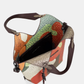 Esta carteira redefine o conceito de versatilidade com uma proposta única: duas carteiras numa só.

A bolsa principal impressiona pelo seu padrão artístico em tons de laranja, verde, bege e terracota, com uma textura trabalhada que evoca o espírito aventureiro e cosmopolita da coleção Odyssey. Os detalhes em metal gunmetal, a corrente com pendente em forma de nuvem e as alças em couro sintético castanho-escuro completam um visual rico e distinto.