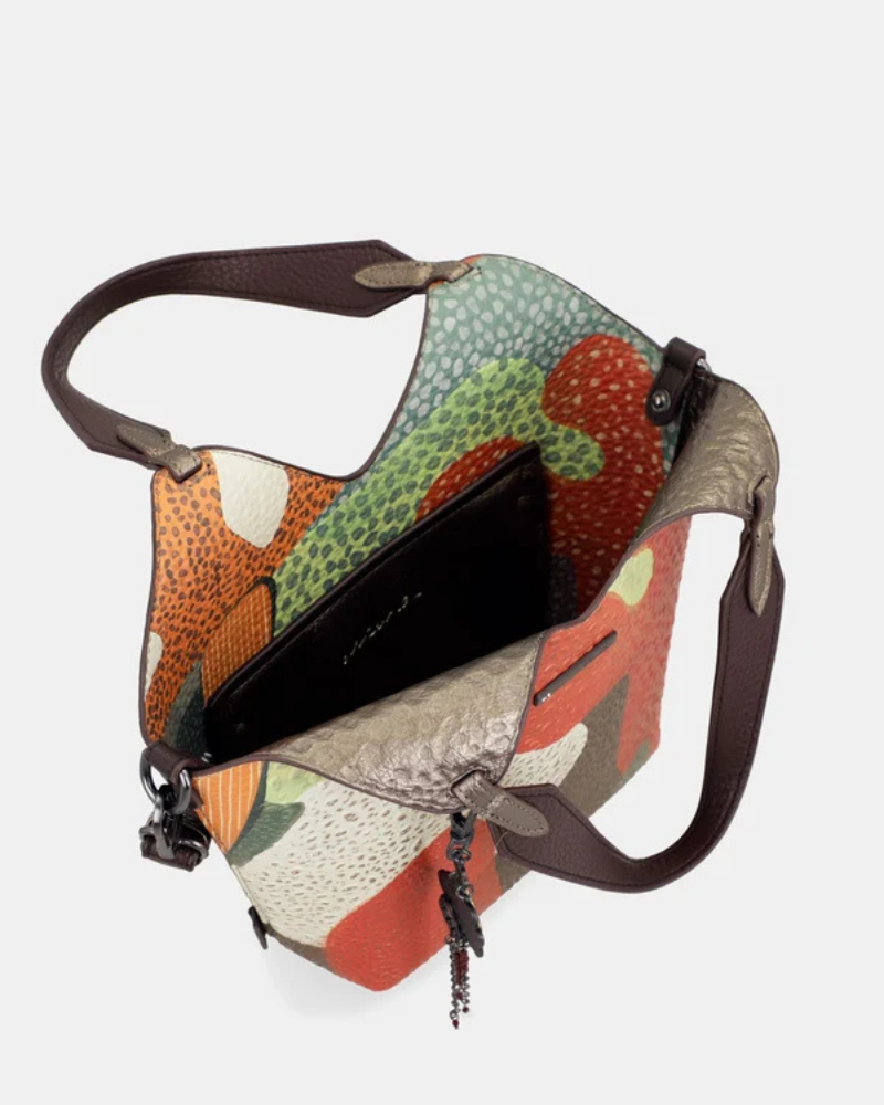 Esta carteira redefine o conceito de versatilidade com uma proposta única: duas carteiras numa só.

A bolsa principal impressiona pelo seu padrão artístico em tons de laranja, verde, bege e terracota, com uma textura trabalhada que evoca o espírito aventureiro e cosmopolita da coleção Odyssey. Os detalhes em metal gunmetal, a corrente com pendente em forma de nuvem e as alças em couro sintético castanho-escuro completam um visual rico e distinto.
