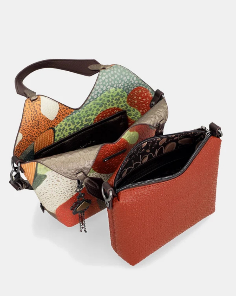 Esta carteira redefine o conceito de versatilidade com uma proposta única: duas carteiras numa só.

A bolsa principal impressiona pelo seu padrão artístico em tons de laranja, verde, bege e terracota, com uma textura trabalhada que evoca o espírito aventureiro e cosmopolita da coleção Odyssey. Os detalhes em metal gunmetal, a corrente com pendente em forma de nuvem e as alças em couro sintético castanho-escuro completam um visual rico e distinto.