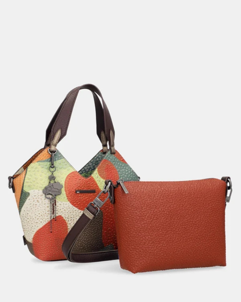 Esta carteira redefine o conceito de versatilidade com uma proposta única: duas carteiras numa só.

A bolsa principal impressiona pelo seu padrão artístico em tons de laranja, verde, bege e terracota, com uma textura trabalhada que evoca o espírito aventureiro e cosmopolita da coleção Odyssey. Os detalhes em metal gunmetal, a corrente com pendente em forma de nuvem e as alças em couro sintético castanho-escuro completam um visual rico e distinto.