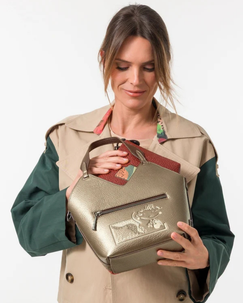 Esta carteira redefine o conceito de versatilidade com uma proposta única: duas carteiras numa só.

A bolsa principal impressiona pelo seu padrão artístico em tons de laranja, verde, bege e terracota, com uma textura trabalhada que evoca o espírito aventureiro e cosmopolita da coleção Odyssey. Os detalhes em metal gunmetal, a corrente com pendente em forma de nuvem e as alças em couro sintético castanho-escuro completam um visual rico e distinto.