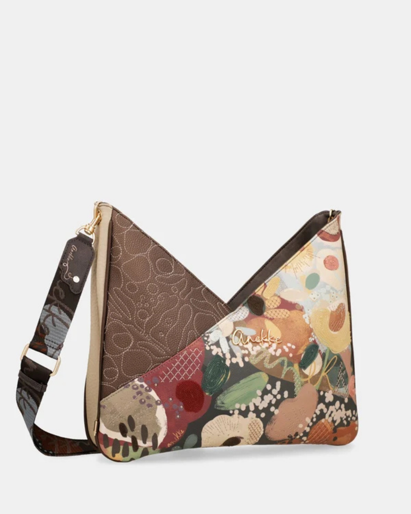 Uma carteira de ombro que celebra a cor, a arte e a liberdade numa peça de grande formato e impacto visual imediato.

O seu design em patchwork combina um painel em couro sintético castanho-escuro com bordado tonal em relevo — onde florescem motivos orgânicos e a silhueta inconfundível da personagem Anekke — com um segundo painel em impressão artística de inspiração botânica, com flores, frutos e manchas de cor em tons de laranja, verde, bege e bordô.