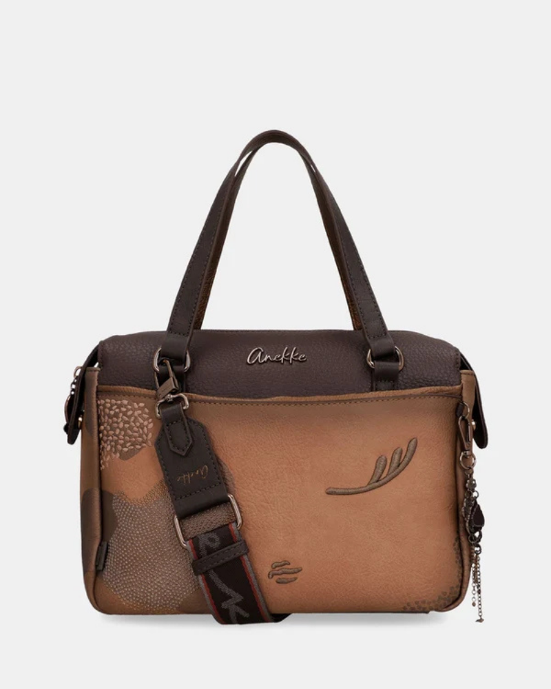 Uma carteira que carrega consigo o espírito da viagem e a sofisticação do detalhe bem executado.

O seu exterior combina couro sintético em tons de bronze envelhecido e castanho-escuro, com aplicações em relevo de motivos florais gravados e silhuetas orgânicas em técnica patchwork — uma composição que evoca mapas antigos, diários de viagem e a beleza do encontro entre culturas. A assinatura Anekke em metal gunmetal e os fechos e argolas em tom escuro completam uma estética coesa e premium.