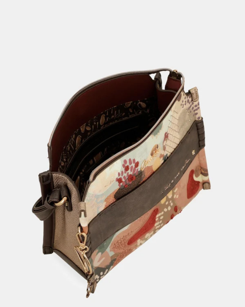 Esta carteira média de tiracolo é cheia de personalidade.

Apresenta um padrão artístico com cenas ilustradas em tons de verde, terracota, bege e bordô, emolduradas por um acabamento em couro sintético preto que lhe confere estrutura e elegância.