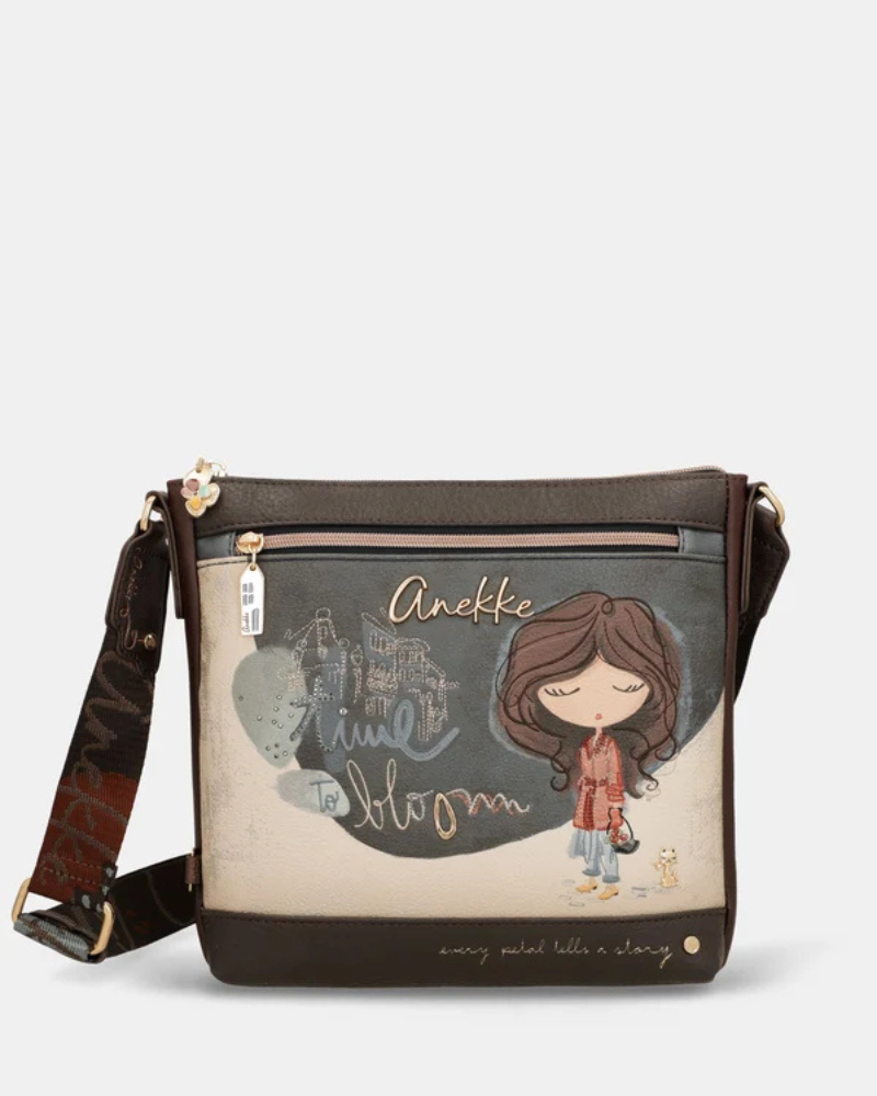 Esta carteira é cheia de personalidade e alma, pensada para a mulher que não abdica do estilo no dia a dia.

De formato horizontal e generoso, combina dois materiais distintos: um parte frontal ilustrada em tons de azul-acinzentado e bege, com a personagem Anekke rodeada de elementos florais e a palavra "Bloom" em letras douradas, e uma base em pele sintética escura que ancora o conjunto com elegância.