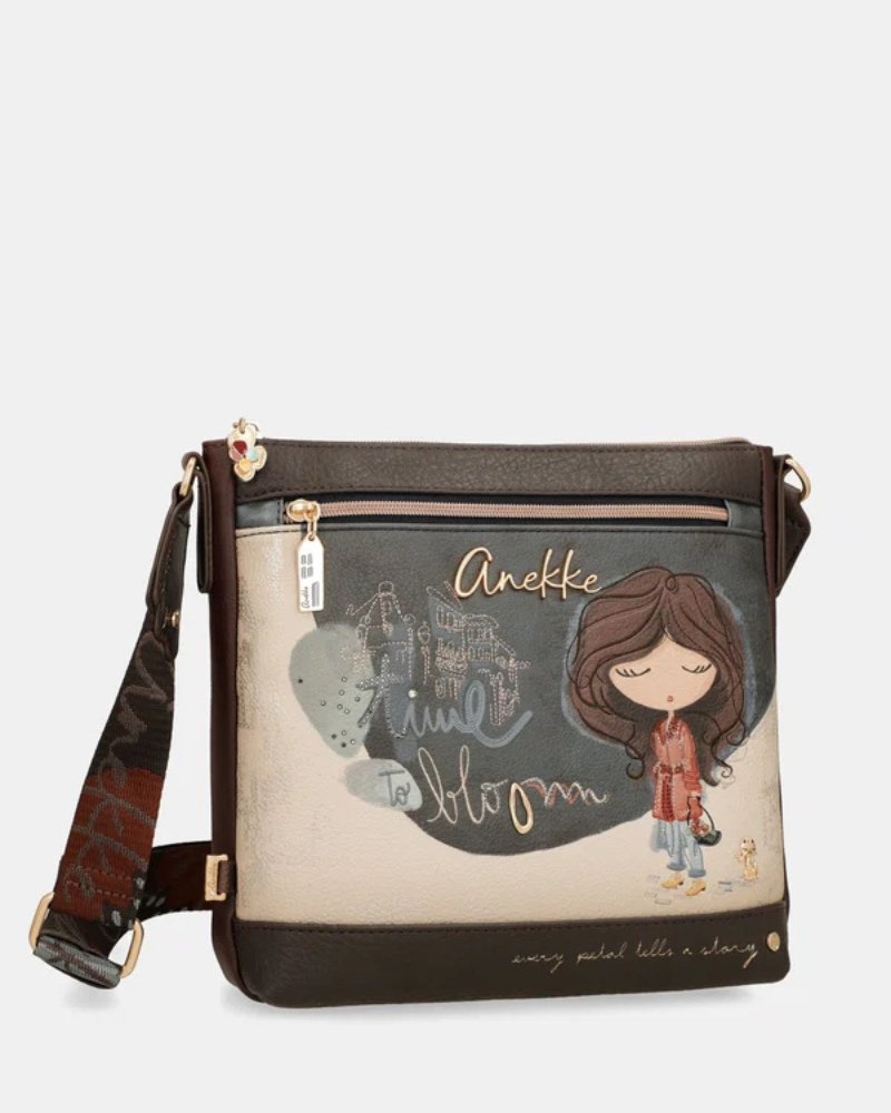 Esta carteira é cheia de personalidade e alma, pensada para a mulher que não abdica do estilo no dia a dia.

De formato horizontal e generoso, combina dois materiais distintos: um parte frontal ilustrada em tons de azul-acinzentado e bege, com a personagem Anekke rodeada de elementos florais e a palavra "Bloom" em letras douradas, e uma base em pele sintética escura que ancora o conjunto com elegância.