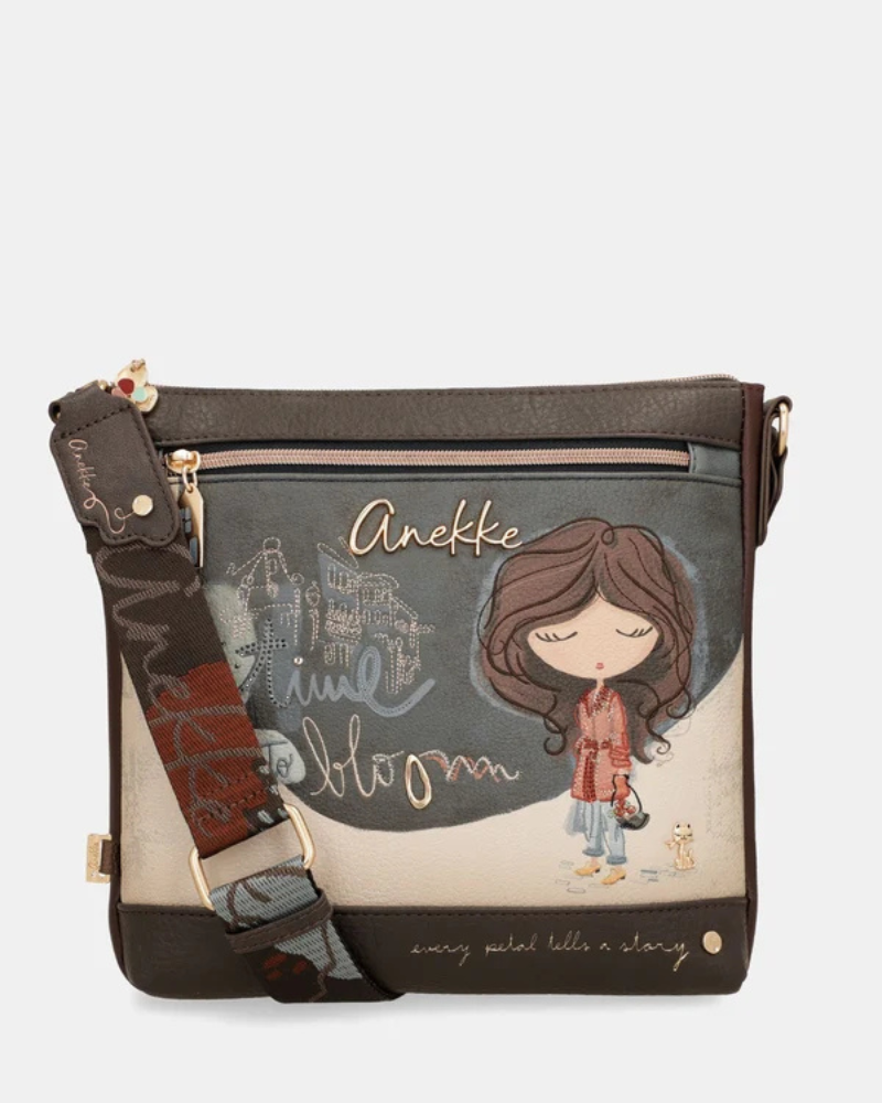 Esta carteira é cheia de personalidade e alma, pensada para a mulher que não abdica do estilo no dia a dia.

De formato horizontal e generoso, combina dois materiais distintos: um parte frontal ilustrada em tons de azul-acinzentado e bege, com a personagem Anekke rodeada de elementos florais e a palavra "Bloom" em letras douradas, e uma base em pele sintética escura que ancora o conjunto com elegância.
