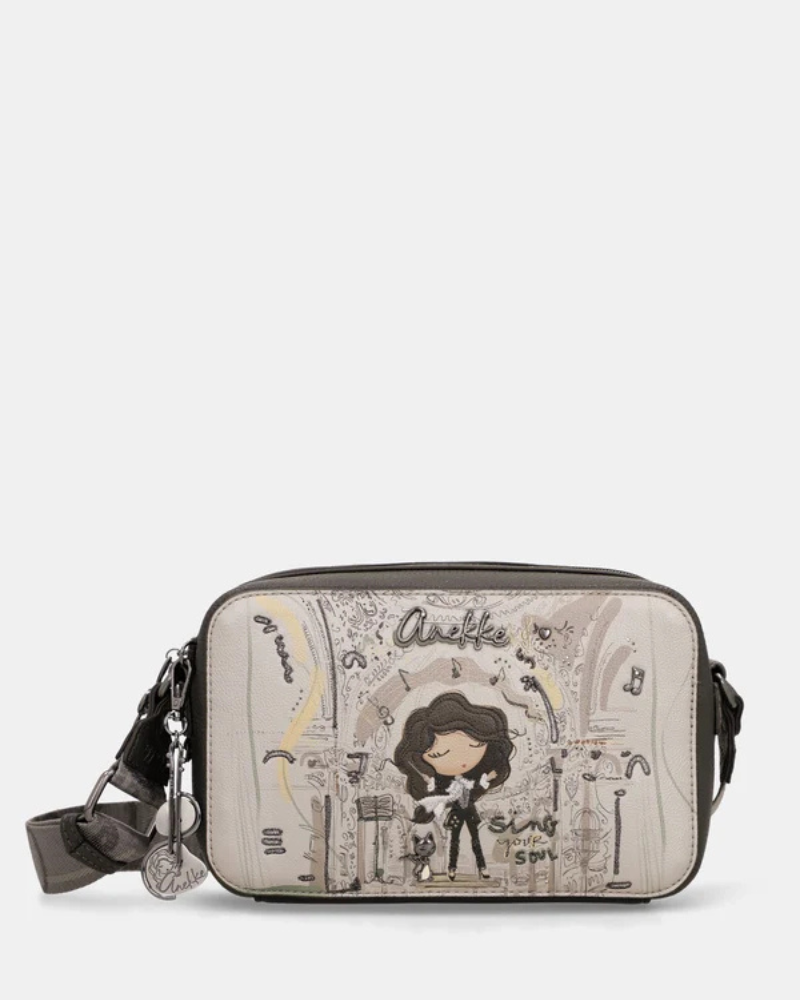 Esta carteira é a companheira perfeita para quem procura estilo e praticidade num formato compacto.

Com uma silhueta retangular e estrutura rígida, esta carteira destaca-se pelo seu acabamento metálico prateado com reflexos pérola, que lhe confere um aspeto sofisticado e contemporâneo. A parte frontal apresenta a ilustração exclusiva da personagem Anekke numa cenografia de inspiração clássica e musical, com detalhes arquitetónicos e elementos de cena que tornam cada peça verdadeiramente única.
