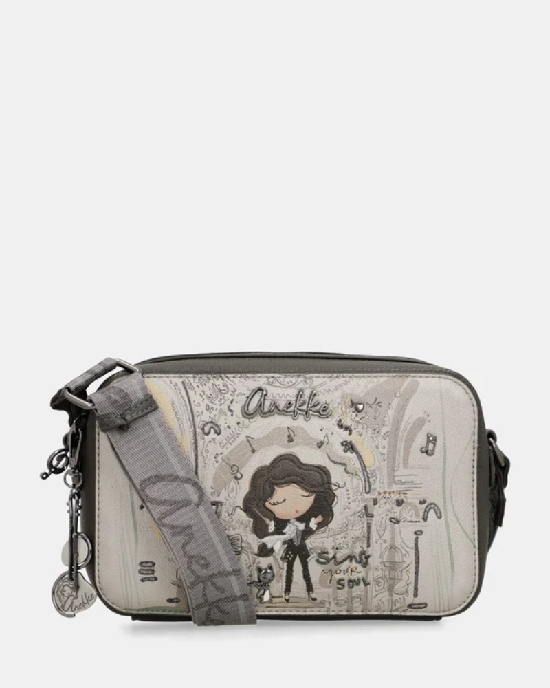 Esta carteira é a companheira perfeita para quem procura estilo e praticidade num formato compacto.

Com uma silhueta retangular e estrutura rígida, esta carteira destaca-se pelo seu acabamento metálico prateado com reflexos pérola, que lhe confere um aspeto sofisticado e contemporâneo. A parte frontal apresenta a ilustração exclusiva da personagem Anekke numa cenografia de inspiração clássica e musical, com detalhes arquitetónicos e elementos de cena que tornam cada peça verdadeiramente única.