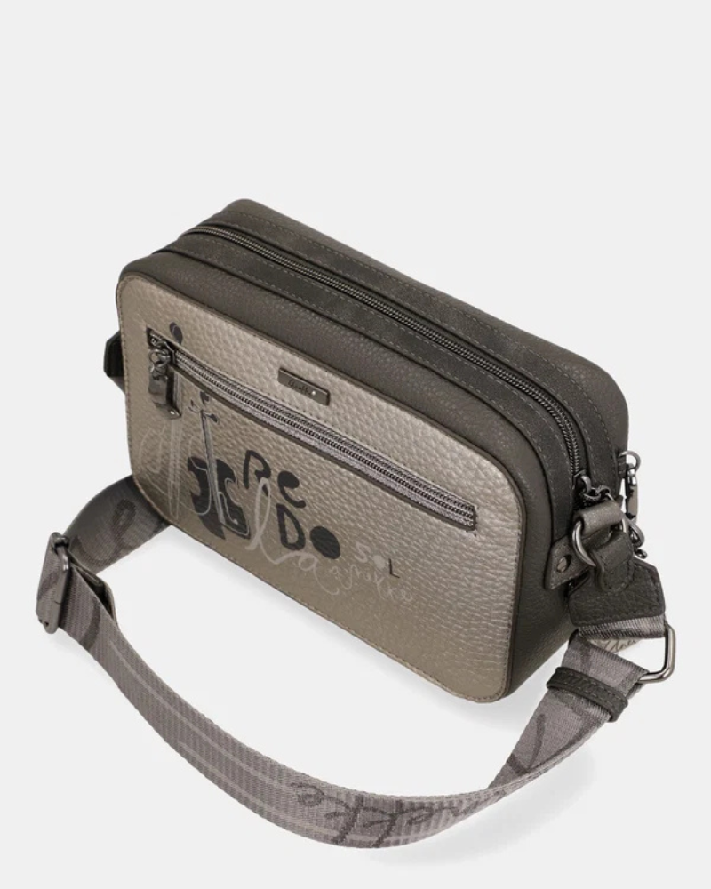 Esta carteira é a companheira perfeita para quem procura estilo e praticidade num formato compacto.

Com uma silhueta retangular e estrutura rígida, esta carteira destaca-se pelo seu acabamento metálico prateado com reflexos pérola, que lhe confere um aspeto sofisticado e contemporâneo. A parte frontal apresenta a ilustração exclusiva da personagem Anekke numa cenografia de inspiração clássica e musical, com detalhes arquitetónicos e elementos de cena que tornam cada peça verdadeiramente única.