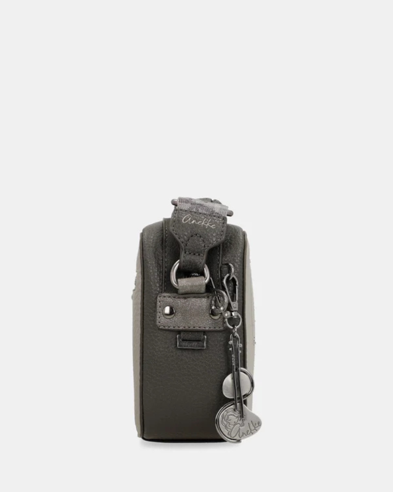 Esta carteira é a companheira perfeita para quem procura estilo e praticidade num formato compacto.

Com uma silhueta retangular e estrutura rígida, esta carteira destaca-se pelo seu acabamento metálico prateado com reflexos pérola, que lhe confere um aspeto sofisticado e contemporâneo. A parte frontal apresenta a ilustração exclusiva da personagem Anekke numa cenografia de inspiração clássica e musical, com detalhes arquitetónicos e elementos de cena que tornam cada peça verdadeiramente única.