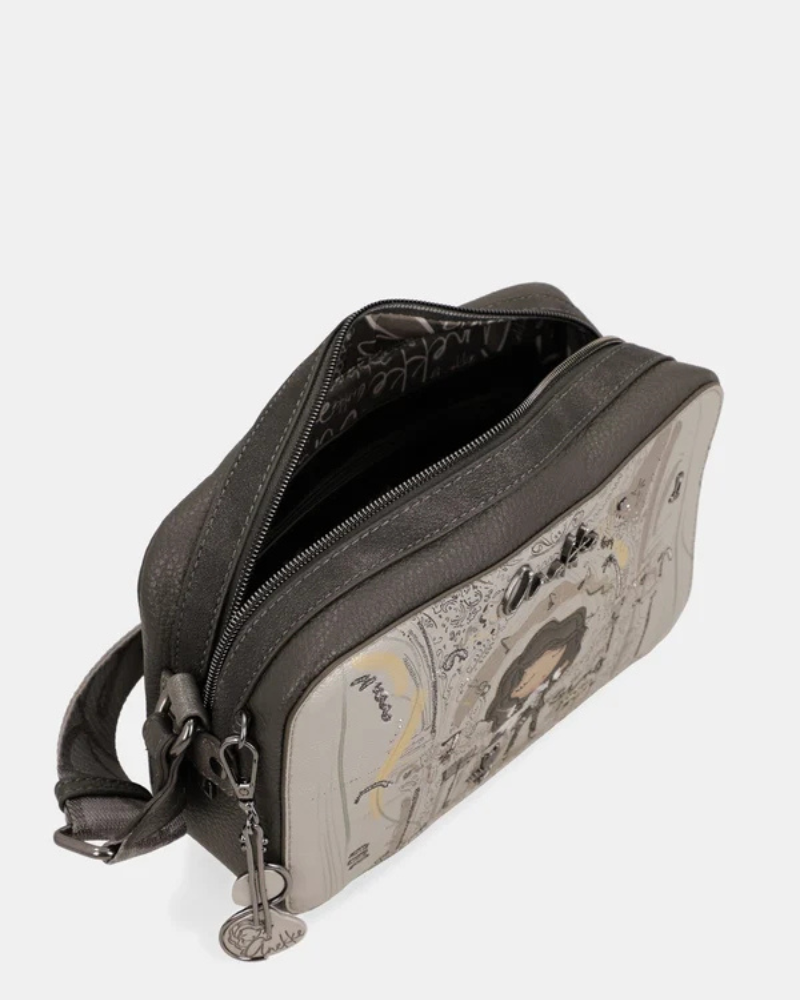 Esta carteira é a companheira perfeita para quem procura estilo e praticidade num formato compacto.

Com uma silhueta retangular e estrutura rígida, esta carteira destaca-se pelo seu acabamento metálico prateado com reflexos pérola, que lhe confere um aspeto sofisticado e contemporâneo. A parte frontal apresenta a ilustração exclusiva da personagem Anekke numa cenografia de inspiração clássica e musical, com detalhes arquitetónicos e elementos de cena que tornam cada peça verdadeiramente única.