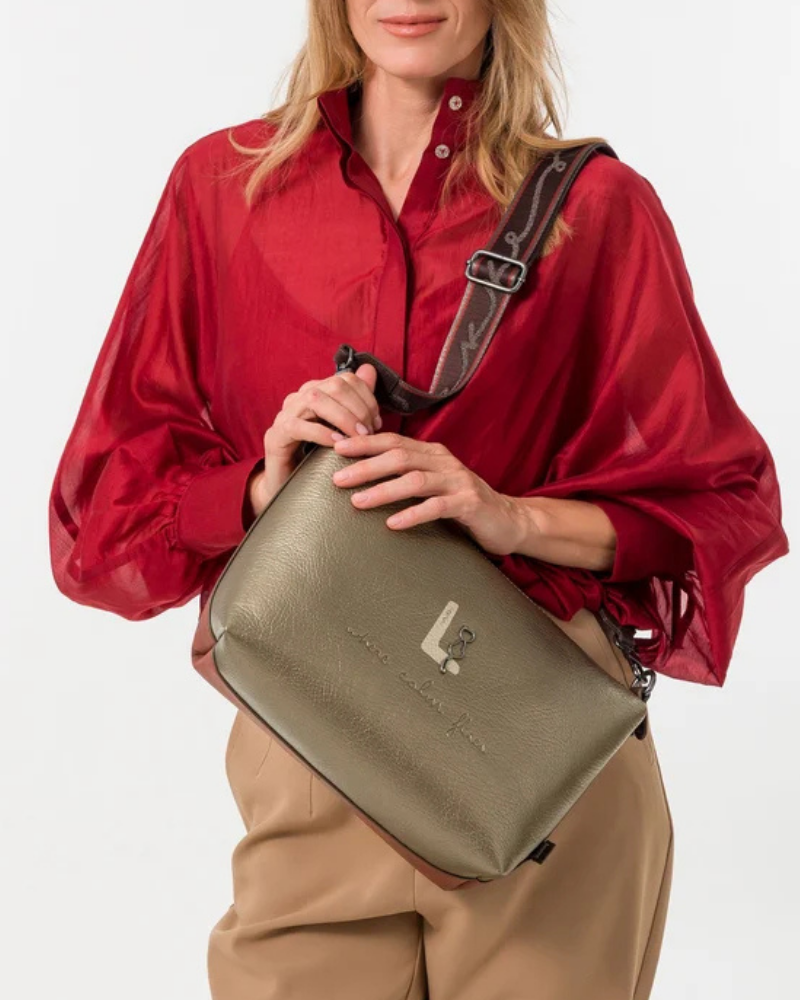 Esta carteira é muito mais do que uma carteira: é um conjunto reversível e modular que oferece duas personalidades num só produto.

A tote principal destaca-se pelo seu padrão artístico em tons de terracota, verde-musgo, laranja e creme, com formas abstratas e texturas em relevo que evocam uma pintura contemporânea. As asas duplas em castanho-escuro, os fechos e argolas em metal gunmetal e o pendente de chaves decorativo completam o design com um toque boémio e editorial.