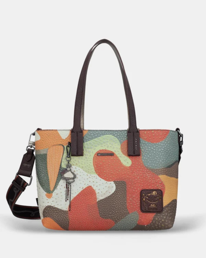 Esta carteira é muito mais do que uma carteira: é um conjunto reversível e modular que oferece duas personalidades num só produto.

A tote principal destaca-se pelo seu padrão artístico em tons de terracota, verde-musgo, laranja e creme, com formas abstratas e texturas em relevo que evocam uma pintura contemporânea. As asas duplas em castanho-escuro, os fechos e argolas em metal gunmetal e o pendente de chaves decorativo completam o design com um toque boémio e editorial.
