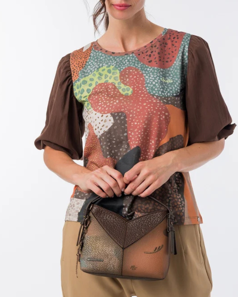 Uma carteira de carácter aventureiro e acabamento sofisticado.

Construída em patchwork de materiais sintéticos com diferentes texturas — grão fino, superfície metálica em cobre envelhecido e painel com estampado pontilhado iridescente —, esta mala de mão combina profundidade visual com uma silhueta estruturada e geométrica.
