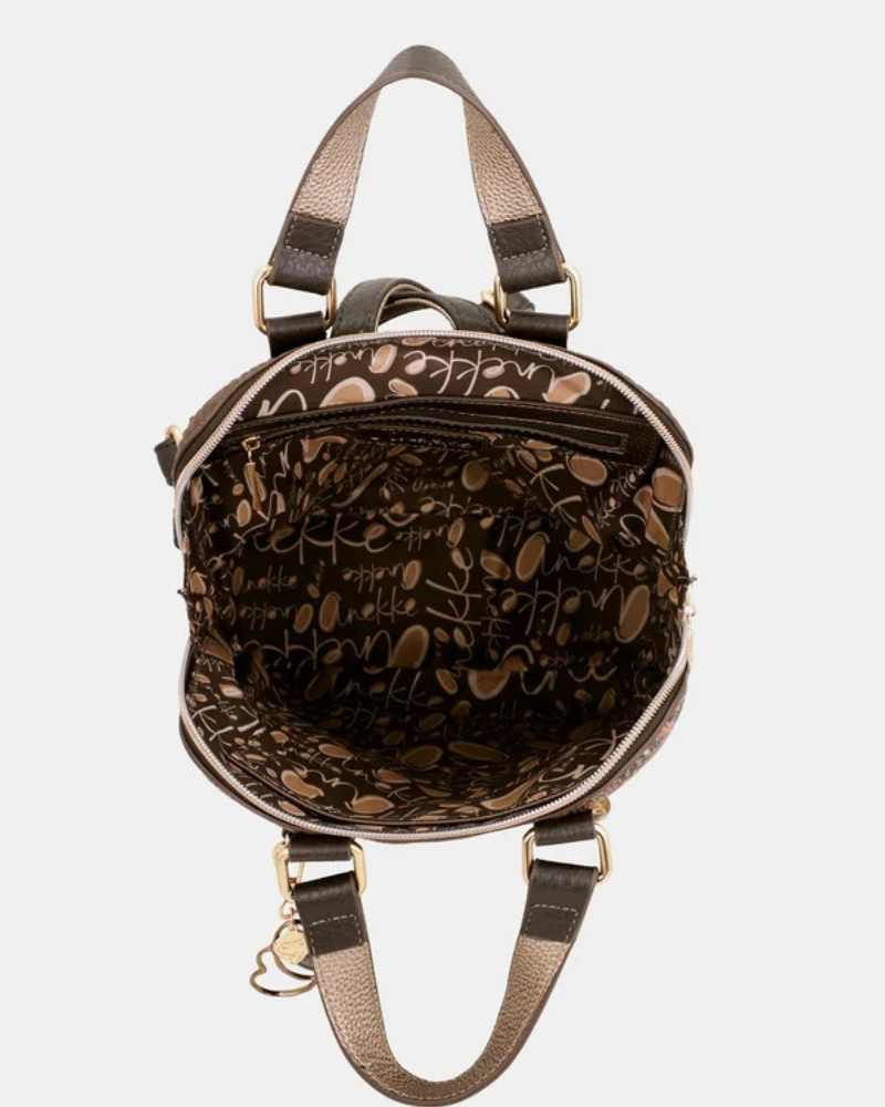 Uma mochila que eleva o conceito de acessório funcional a verdadeira peça de autor.

O seu exterior apresenta um padrão em patchwork com texturas e motivos em tons de verde-musgo, castanho, terracota e dourado, com apontamentos florais e geométricos que evocam a riqueza dos tecidos artesanais. A assinatura Anekke em lettering dourado, os detalhes em metal dourado e o pendente com logótipo completam um design sofisticado e inconfundível.