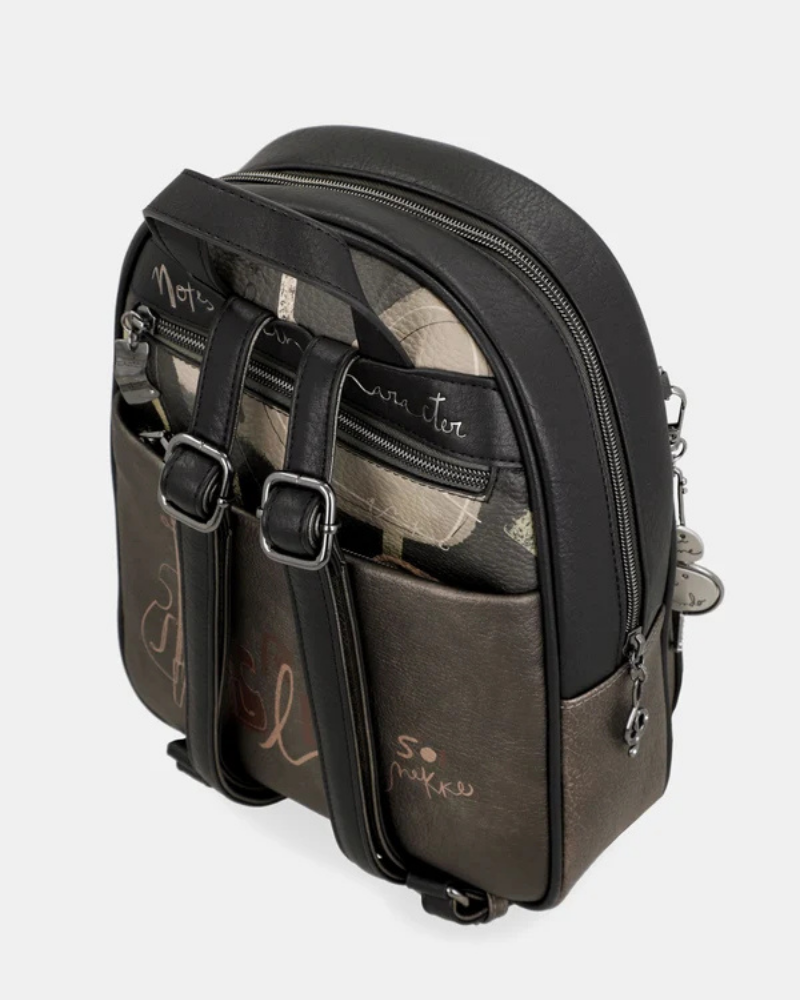 Esta mochila é uma peça para quem encontra beleza na arte urbana e no detalhe inesperado.

O seu exterior combina couro sintético preto com um painel central em tom bronze-caqui, decorado com lettering fluido de inspiração graffiti — o mesmo ADN criativo que define toda a coleção Melody. A assinatura Anekke bordada, os pendentes em metal prateado e os fechos duplos conferem-lhe uma personalidade arrojada e distinta.