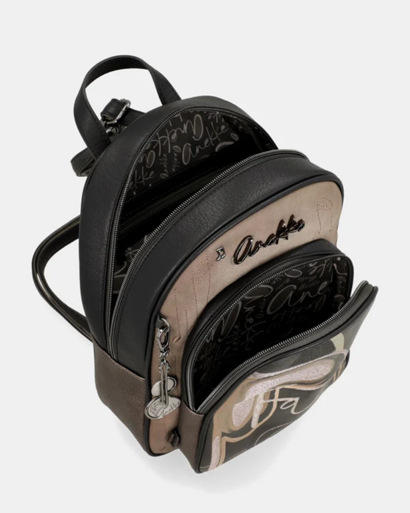 Esta mochila é uma peça para quem encontra beleza na arte urbana e no detalhe inesperado.

O seu exterior combina couro sintético preto com um painel central em tom bronze-caqui, decorado com lettering fluido de inspiração graffiti — o mesmo ADN criativo que define toda a coleção Melody. A assinatura Anekke bordada, os pendentes em metal prateado e os fechos duplos conferem-lhe uma personalidade arrojada e distinta.