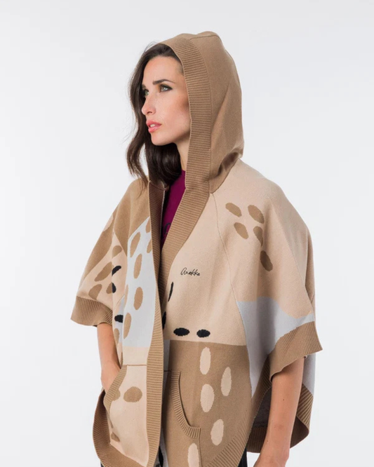 Este poncho é uma peça versátil que combina conforto e sofisticação numa silhueta única.

Confeccionado em malha de qualidade premium, apresenta um padrão exclusivo inspirado na girafa, com manchas em tons de bege, creme e preto que lhe conferem um carácter editorial e atemporal. O capuz estruturado com acabamento em canelado, as mangas curtas amplas e os bolsos frontais tornam-no tão funcional quanto elegante. 