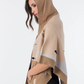 Este poncho é uma peça versátil que combina conforto e sofisticação numa silhueta única.

Confeccionado em malha de qualidade premium, apresenta um padrão exclusivo inspirado na girafa, com manchas em tons de bege, creme e preto que lhe conferem um carácter editorial e atemporal. O capuz estruturado com acabamento em canelado, as mangas curtas amplas e os bolsos frontais tornam-no tão funcional quanto elegante. 