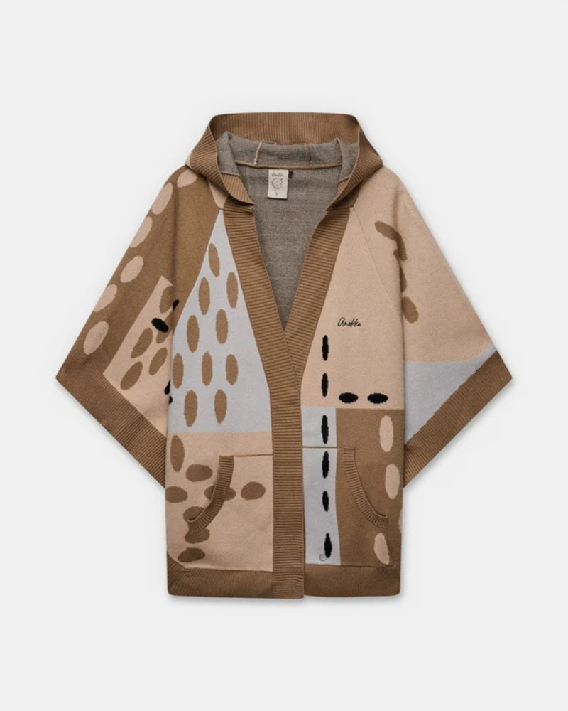 Este poncho é uma peça versátil que combina conforto e sofisticação numa silhueta única.

Confeccionado em malha de qualidade premium, apresenta um padrão exclusivo inspirado na girafa, com manchas em tons de bege, creme e preto que lhe conferem um carácter editorial e atemporal. O capuz estruturado com acabamento em canelado, as mangas curtas amplas e os bolsos frontais tornam-no tão funcional quanto elegante. 