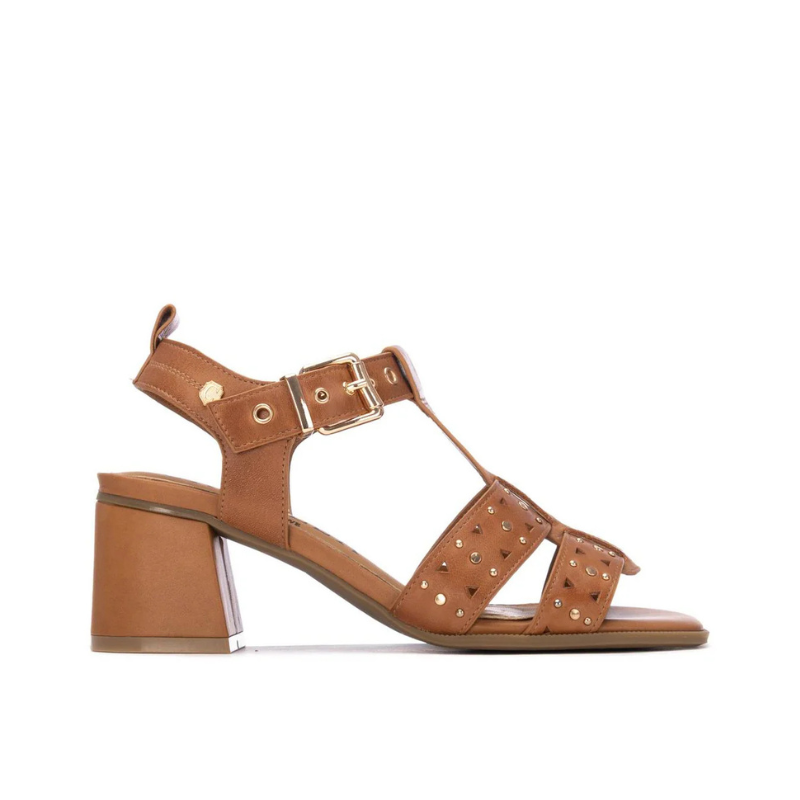 Esta sandália camel combina feminilidade e atitude numa silhueta de salto bloco médio.

As tiras em T com recortes geométricos e aplicações de tachas douradas conferem personalidade e detalhe ao design, enquanto a fivela dourada no tornozelo garante um ajuste seguro e elegante. O salto bloco de altura média oferece conforto e estabilidade ao longo do dia, tornando-a uma escolha versátil para ocasiões que pedem um toque mais sofisticado.