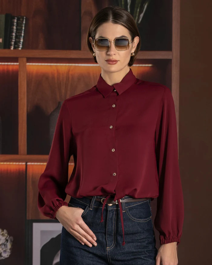 Este camiseiro combina um design clássico com um toque moderno e feminino.

Apresenta gola tradicional, fecho frontal com botões e mangas compridas com punhos ligeiramente franzidos, enquanto o cordão de ajuste na parte inferior permite definir a silhueta e adaptar o caimento ao gosto de cada pessoa.