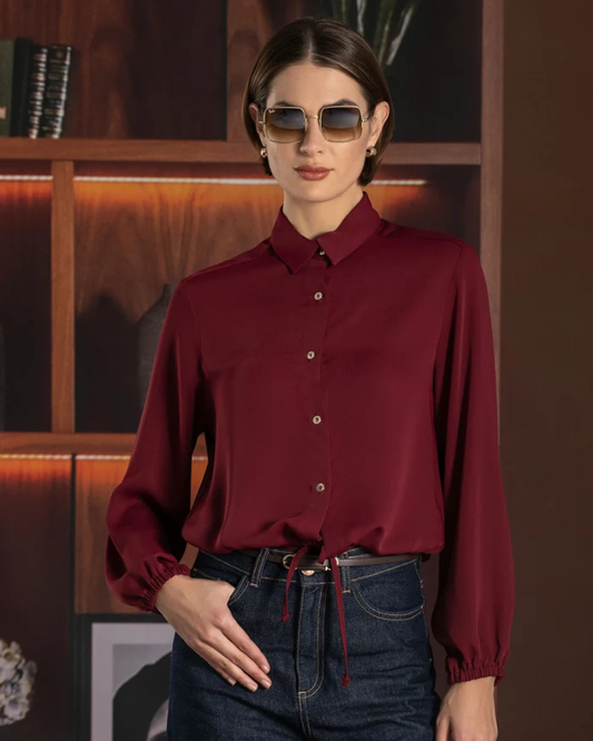 Este camiseiro combina um design clássico com um toque moderno e feminino.

Apresenta gola tradicional, fecho frontal com botões e mangas compridas com punhos ligeiramente franzidos, enquanto o cordão de ajuste na parte inferior permite definir a silhueta e adaptar o caimento ao gosto de cada pessoa.