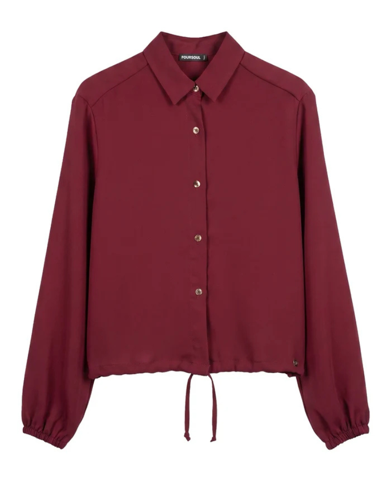 Este camiseiro combina um design clássico com um toque moderno e feminino.

Apresenta gola tradicional, fecho frontal com botões e mangas compridas com punhos ligeiramente franzidos, enquanto o cordão de ajuste na parte inferior permite definir a silhueta e adaptar o caimento ao gosto de cada pessoa.