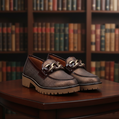 Este mocassim destaca-se pelo seu design elegante e atual, em tom castanho com acabamento texturado que acrescenta personalidade ao modelo.

O detalhe de corrente metálica dourada sobre a pala confere um toque sofisticado, enquanto a sola robusta com piso tratorado oferece um visual moderno e cheio de atitude.