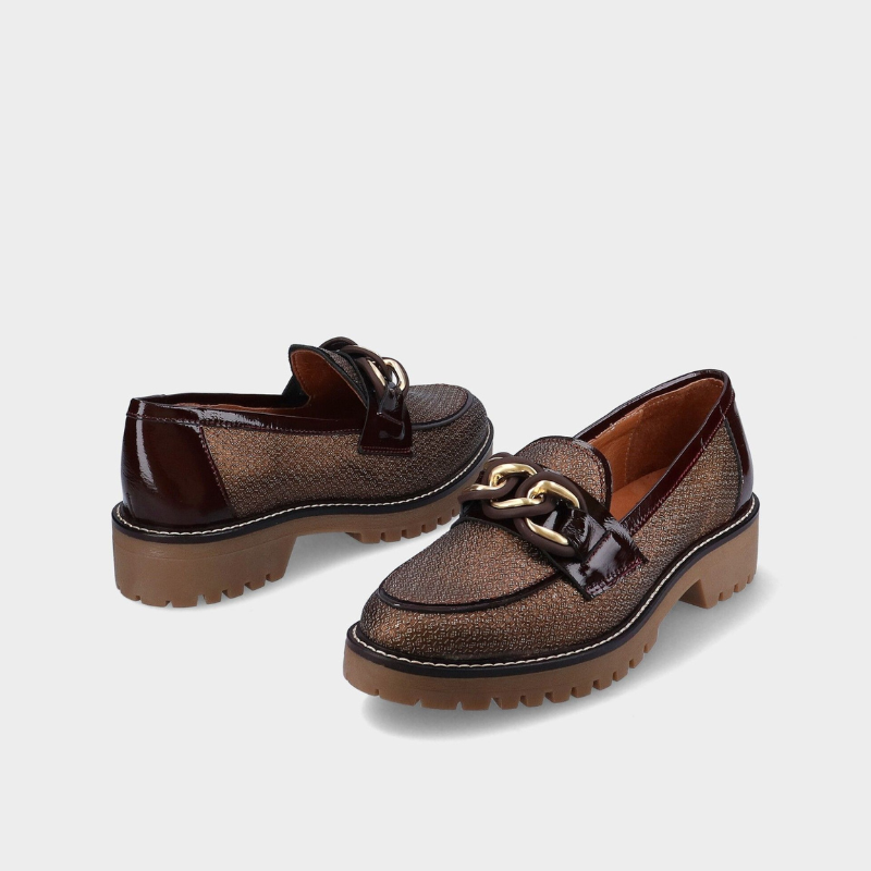 Este mocassim destaca-se pelo seu design elegante e atual, em tom castanho com acabamento texturado que acrescenta personalidade ao modelo.

O detalhe de corrente metálica dourada sobre a pala confere um toque sofisticado, enquanto a sola robusta com piso tratorado oferece um visual moderno e cheio de atitude.
