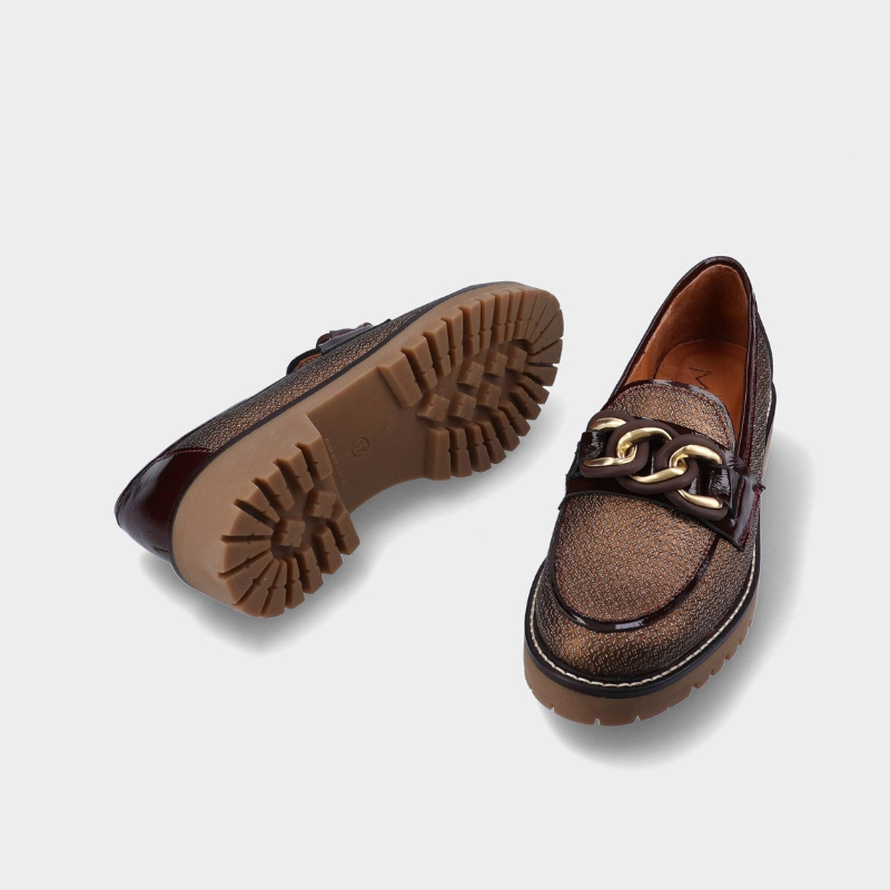 Este mocassim destaca-se pelo seu design elegante e atual, em tom castanho com acabamento texturado que acrescenta personalidade ao modelo.

O detalhe de corrente metálica dourada sobre a pala confere um toque sofisticado, enquanto a sola robusta com piso tratorado oferece um visual moderno e cheio de atitude.