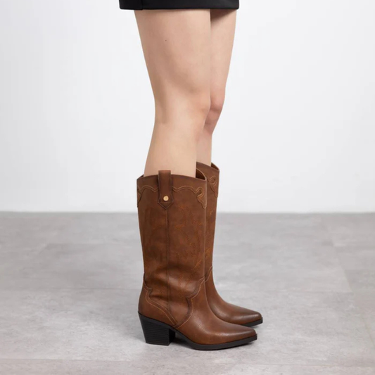 Esta bota texana de cano alto é a escolha perfeita para quem deseja um estilo marcante e versátil.

Produzida em material sintético de alta qualidade, ela apresenta acabamento em tom terroso e detalhes de bordados que valorizam seu design clássico western. O salto bloco médio garante conforto e estabilidade, permitindo o uso prolongado sem esquecer a elegância. Com forma bicuda levemente afinada e puxadores laterais, facilita o calçar e adiciona personalidade ao visual.