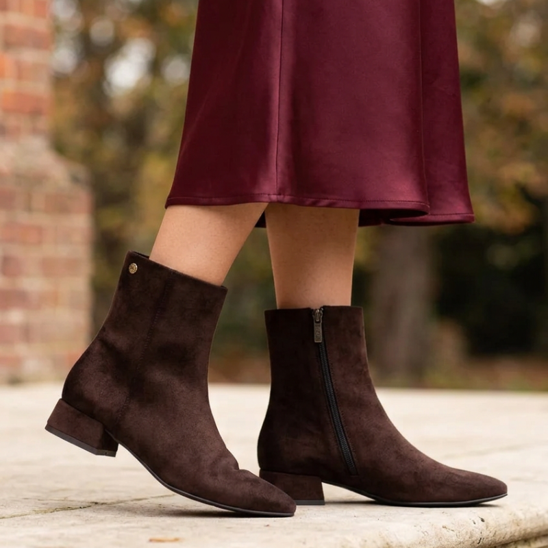 Este botim castanho-escuro combina elegância e versatilidade, sendo uma escolha perfeita para complementar os seus looks de outono e inverno.

O acabamento aveludado confere-lhe um toque sofisticado, enquanto a biqueira pontiaguda e o salto baixo e largo criam uma silhueta elegante e equilibrada. O pequeno detalhe metálico na lateral acrescenta um apontamento discreto, e o fecho de correr no lado interior facilita o calçar.