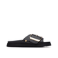 Minimalista e com um impacto visual inegável, este chinelo plano em preto é uma peça que redefine o conceito de casual chic.

A tira larga e estruturada, decorada com uma fivela oversized em dourado, transforma um modelo de inspiração clássica numa declaração de estilo contemporânea. A sola plataforma em borracha preta, ligeiramente elevada, confere conforto e estabilidade ao longo do dia, enquanto a palmilha macia acompanha o pé com suavidade.