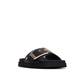 Minimalista e com um impacto visual inegável, este chinelo plano em preto é uma peça que redefine o conceito de casual chic.

A tira larga e estruturada, decorada com uma fivela oversized em dourado, transforma um modelo de inspiração clássica numa declaração de estilo contemporânea. A sola plataforma em borracha preta, ligeiramente elevada, confere conforto e estabilidade ao longo do dia, enquanto a palmilha macia acompanha o pé com suavidade.