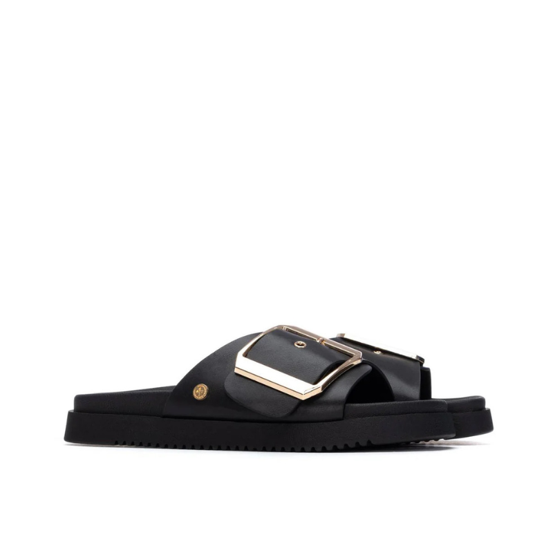 Minimalista e com um impacto visual inegável, este chinelo plano em preto é uma peça que redefine o conceito de casual chic.

A tira larga e estruturada, decorada com uma fivela oversized em dourado, transforma um modelo de inspiração clássica numa declaração de estilo contemporânea. A sola plataforma em borracha preta, ligeiramente elevada, confere conforto e estabilidade ao longo do dia, enquanto a palmilha macia acompanha o pé com suavidade.