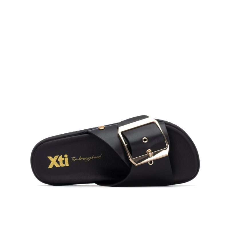 Minimalista e com um impacto visual inegável, este chinelo plano em preto é uma peça que redefine o conceito de casual chic.

A tira larga e estruturada, decorada com uma fivela oversized em dourado, transforma um modelo de inspiração clássica numa declaração de estilo contemporânea. A sola plataforma em borracha preta, ligeiramente elevada, confere conforto e estabilidade ao longo do dia, enquanto a palmilha macia acompanha o pé com suavidade.