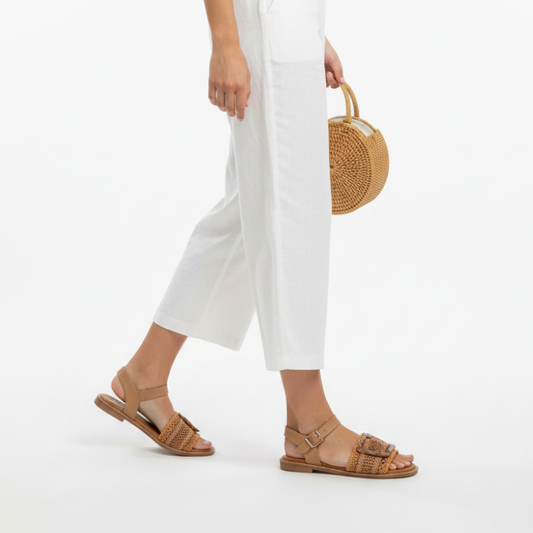Com um design casual e contemporâneo, esta sandália rasa em rafia trançada é a escolha perfeita para os dias em que o conforto e o estilo andam de mãos dadas.

A tira em material trançado confere leveza e textura ao modelo, enquanto a fivela quadrada de grande dimensão em preto brilhante adiciona um toque moderno e arrojado.